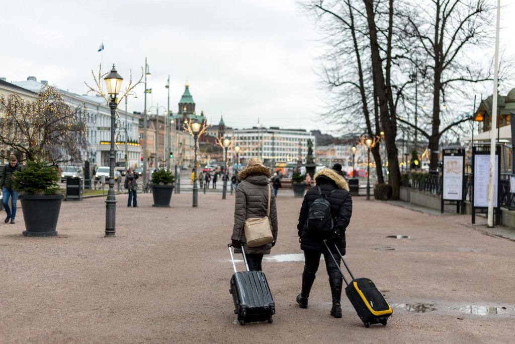 Tourists with luggage stroll through Helsinki on a cloudy day.