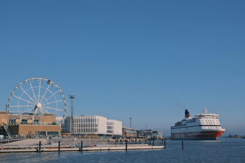 A bustling harbor view showcasing a cruise ship near a Ferris wheel on a clear day.