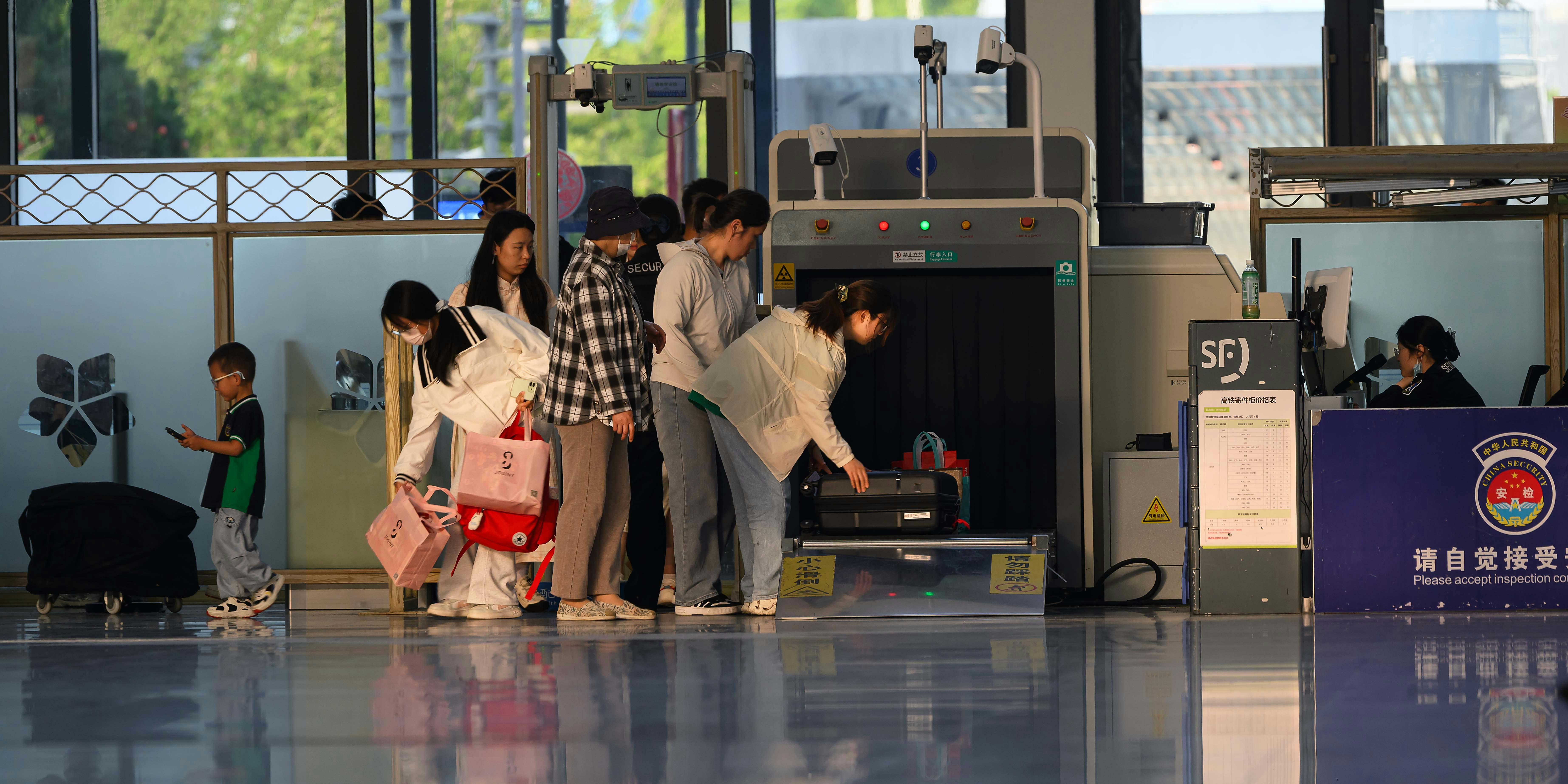 Crowded airport check-in area with people queueing and visible flight information signs.